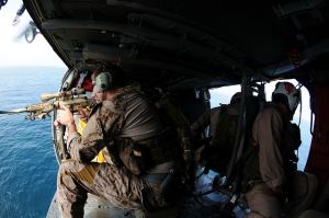 U.S. Navy SEAL fires an MK11 sniper rifle from an MH-60S Knighthawk helicopter, assigned to Helicopter Sea Combat Squadron (HSC) 9 and deployed with the aircraft carrier USS George H.W. Bush (CVN 77) during a training flight in the Arabian Sea. (Photo Credit: U.S. Navy)